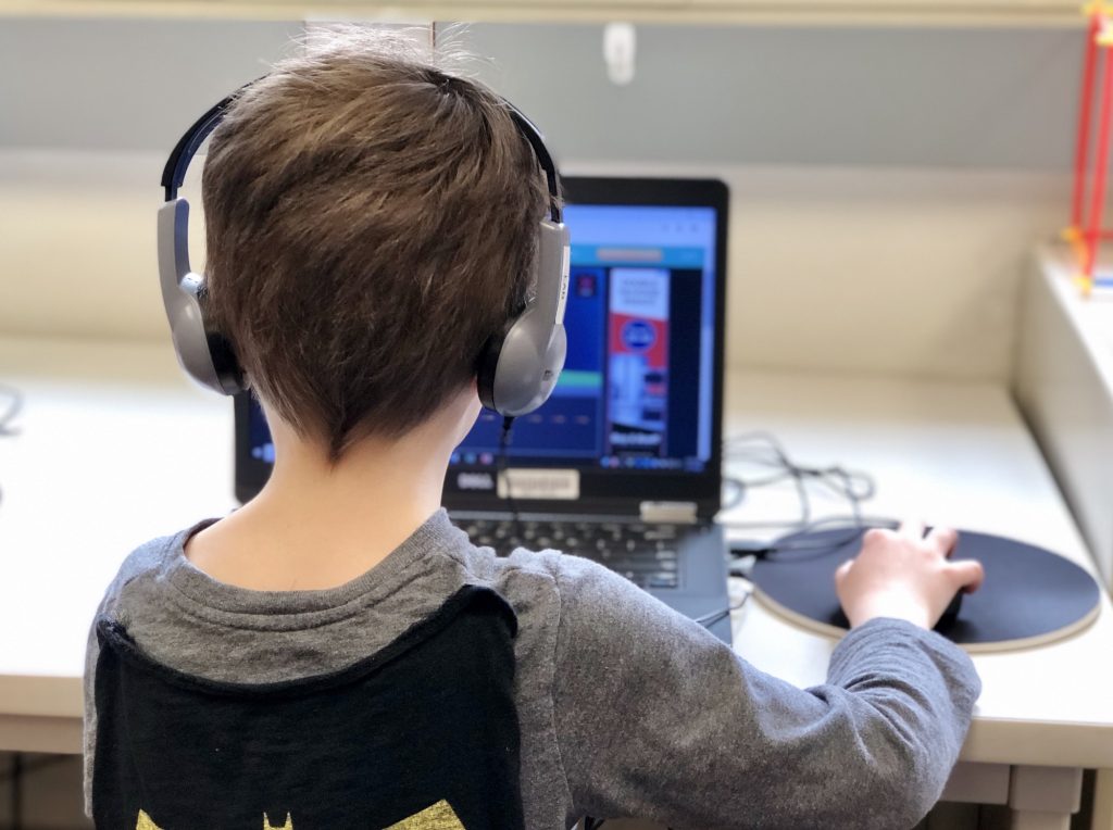 Child using computer for school with headphones on